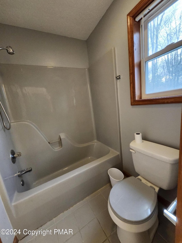 full bath featuring tile patterned flooring, a textured ceiling, toilet, and shower / bath combination