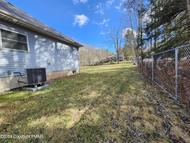 view of yard featuring fence and central AC