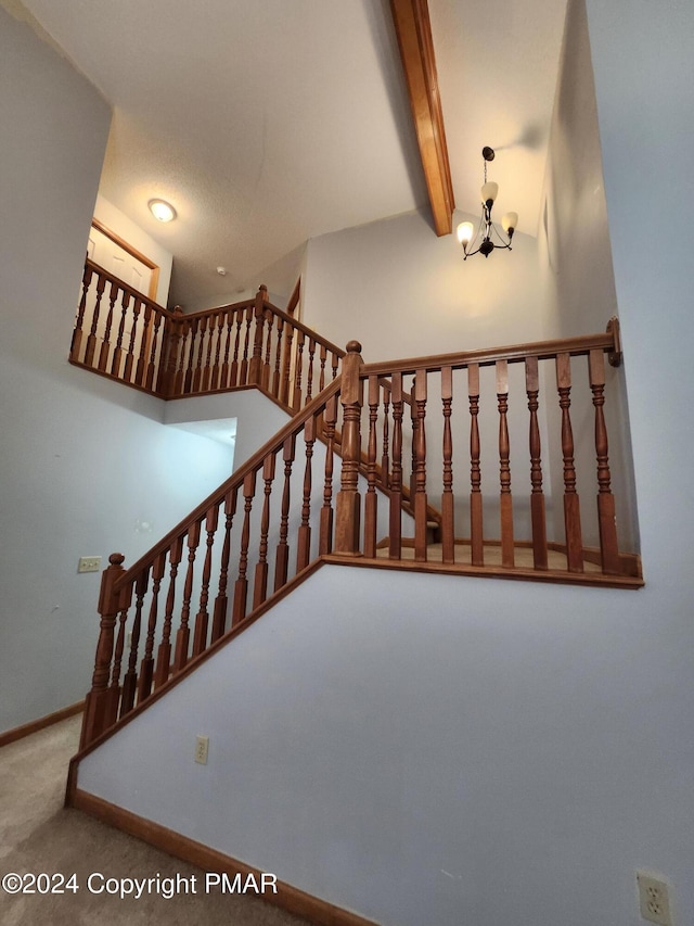 stairs with a notable chandelier, beamed ceiling, baseboards, and carpet