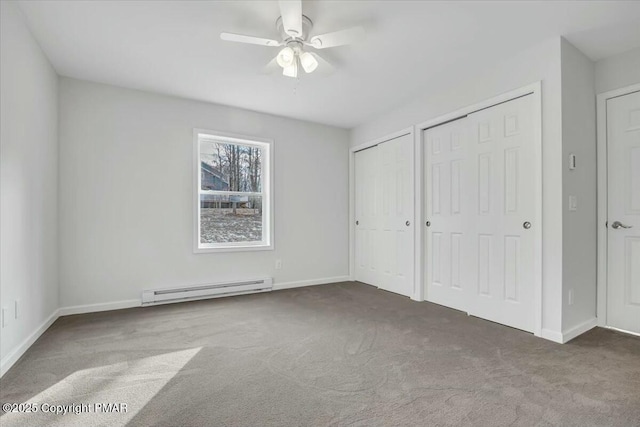 unfurnished bedroom featuring carpet floors, multiple closets, a baseboard heating unit, ceiling fan, and baseboards