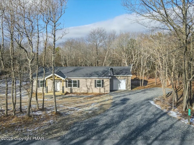 view of front of home with a garage, driveway, and a view of trees