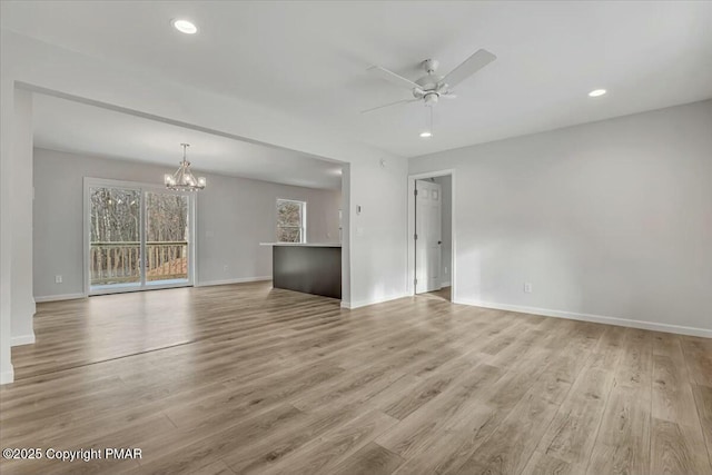 unfurnished living room with recessed lighting, baseboards, light wood finished floors, and ceiling fan with notable chandelier