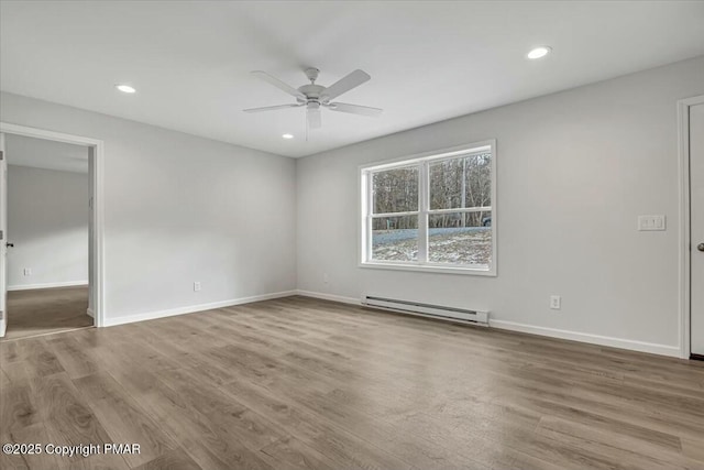 unfurnished room with a baseboard radiator, baseboards, and wood finished floors