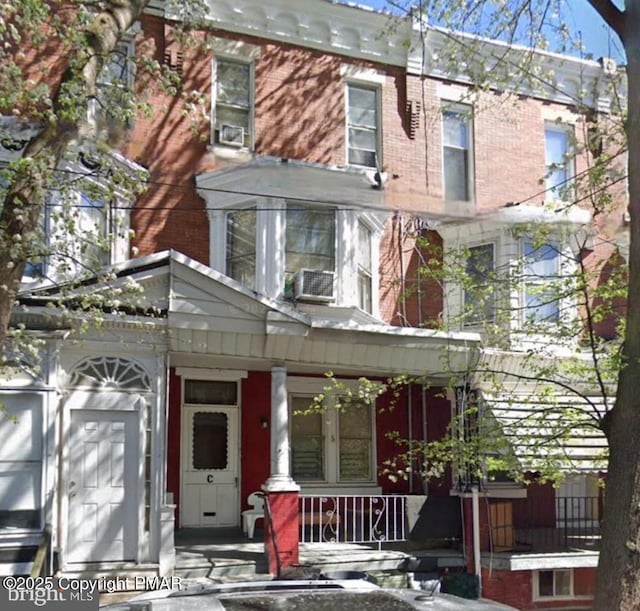 view of front of house with a porch, cooling unit, and brick siding