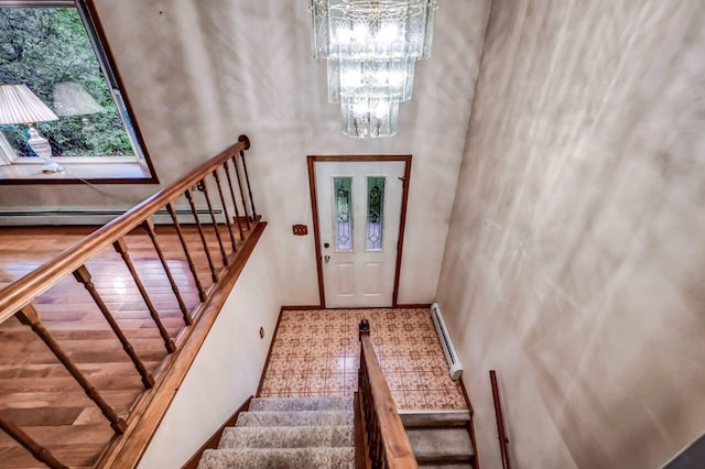 entryway with a chandelier, stairway, baseboard heating, a baseboard radiator, and baseboards
