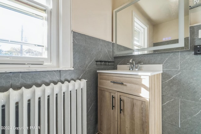 bathroom featuring a wealth of natural light, tile walls, vanity, and radiator heating unit