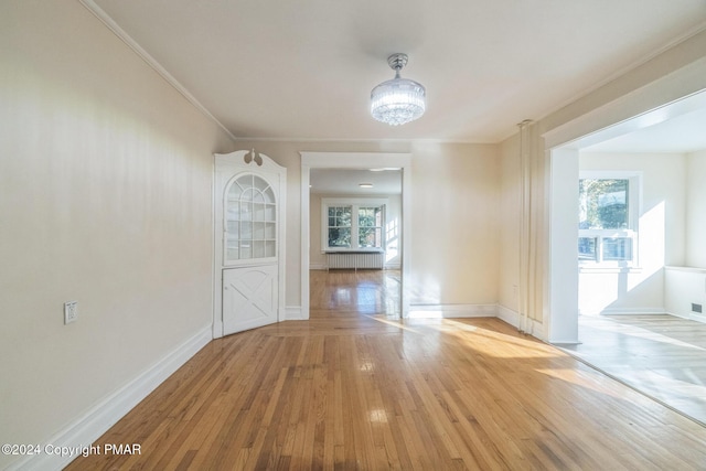 unfurnished dining area with plenty of natural light, ornamental molding, wood-type flooring, and baseboards