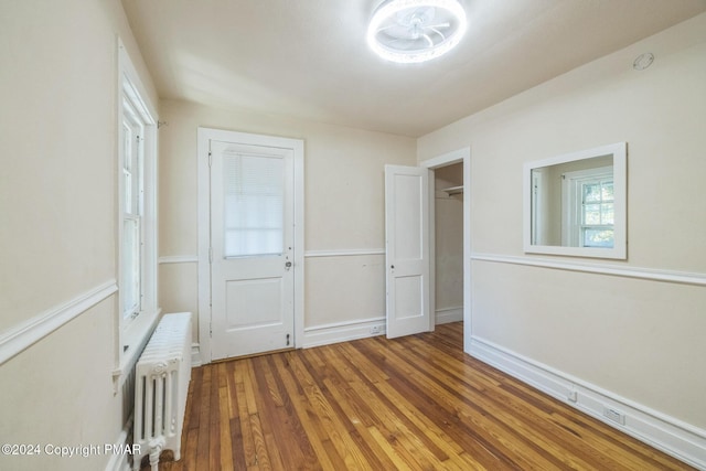 unfurnished bedroom featuring radiator and wood finished floors