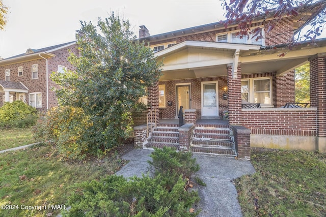 view of front facade with covered porch and brick siding