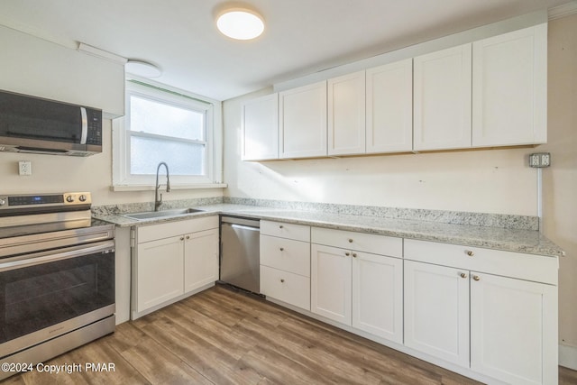 kitchen with stainless steel appliances, white cabinetry, and a sink