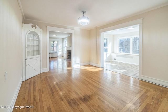 interior space featuring crown molding, a fireplace, light wood finished floors, and radiator heating unit