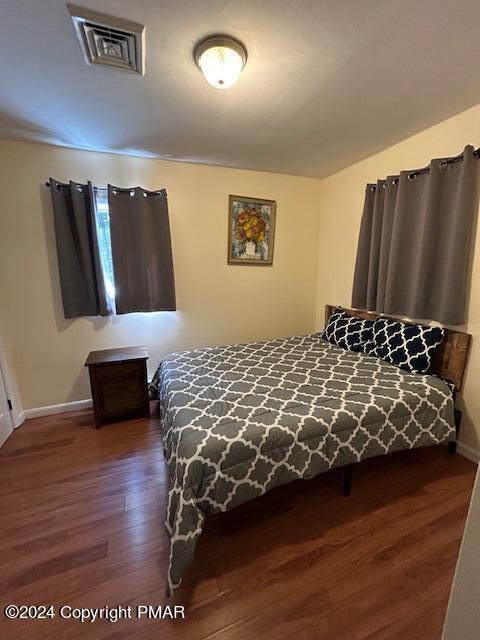 bedroom featuring visible vents, baseboards, and wood finished floors