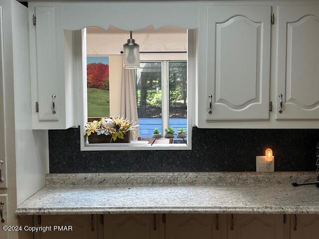 kitchen featuring decorative backsplash, light countertops, and white cabinetry