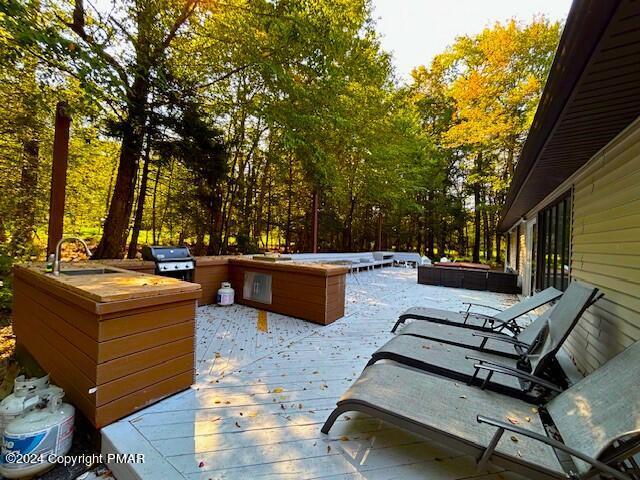 deck with a grill, a jacuzzi, and a sink