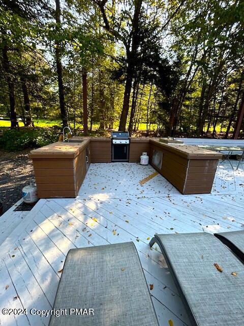 exterior space with a wooden deck, a grill, a jacuzzi, and a sink