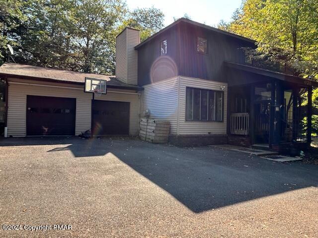 view of front of home with a garage, driveway, and a chimney