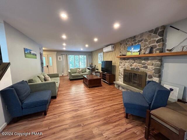 living area featuring recessed lighting, a fireplace, a wall mounted AC, and light wood-style floors