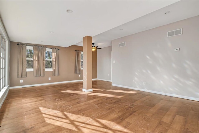 unfurnished living room featuring a ceiling fan, wood finished floors, visible vents, and baseboards