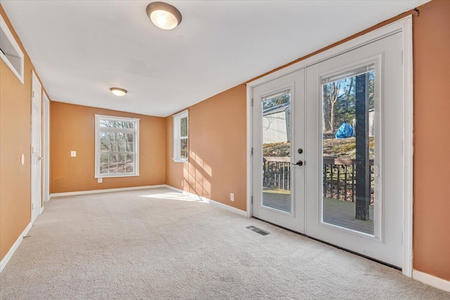 empty room with carpet flooring, french doors, visible vents, and baseboards