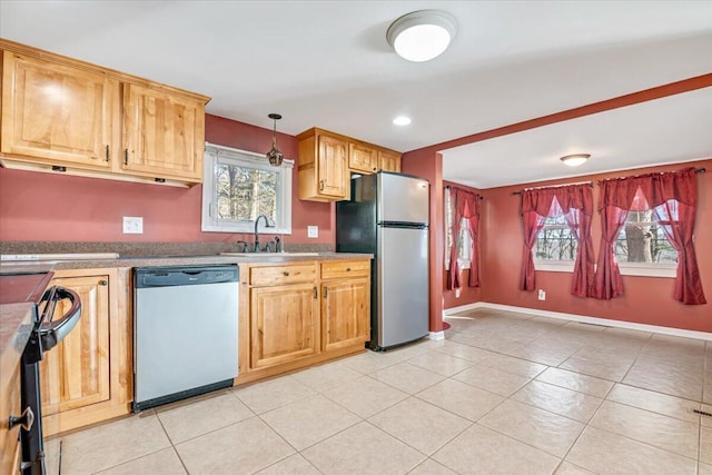 kitchen with a sink, stainless steel appliances, baseboards, and a healthy amount of sunlight