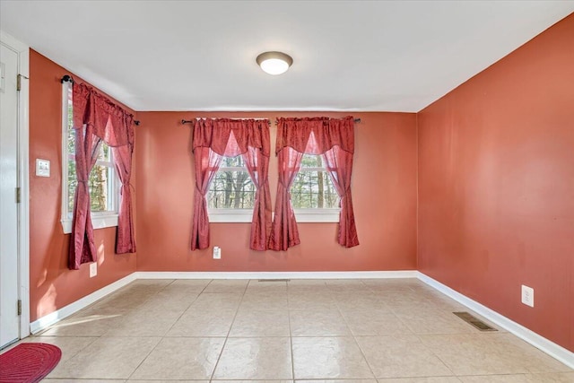 tiled spare room with a wealth of natural light, visible vents, and baseboards