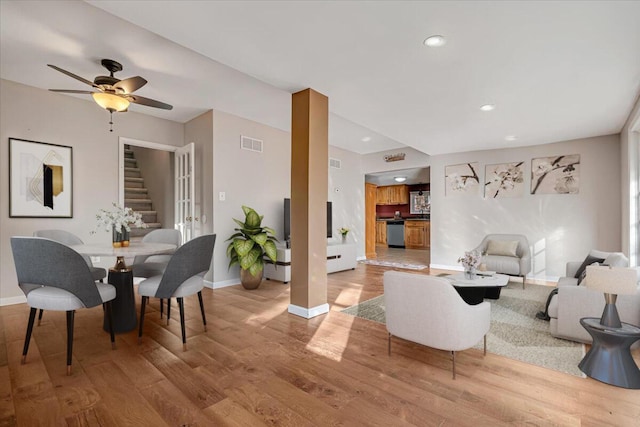 living area featuring visible vents, baseboards, wood finished floors, and stairs