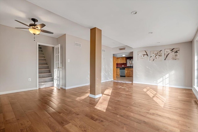 unfurnished living room featuring visible vents, stairs, baseboards, and wood finished floors