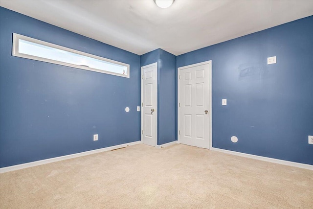 unfurnished bedroom with baseboards and light carpet