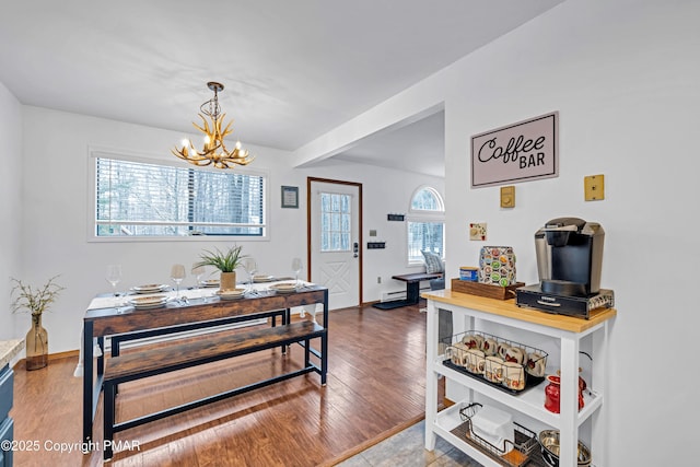 dining area with a wealth of natural light, a notable chandelier, and wood finished floors