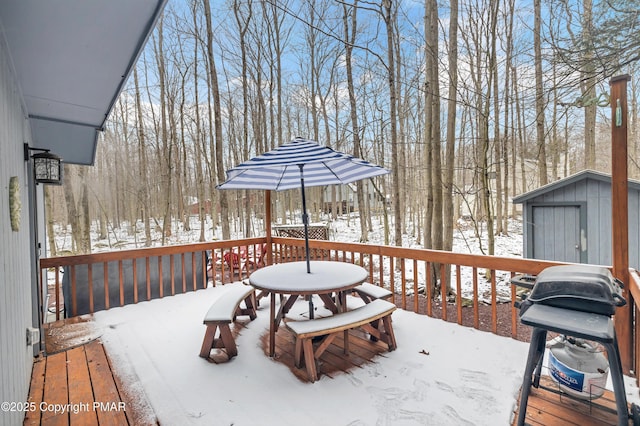 snow covered deck featuring an outbuilding and a storage unit