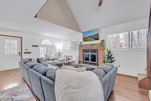 living room with a ceiling fan, a brick fireplace, wood finished floors, and high vaulted ceiling