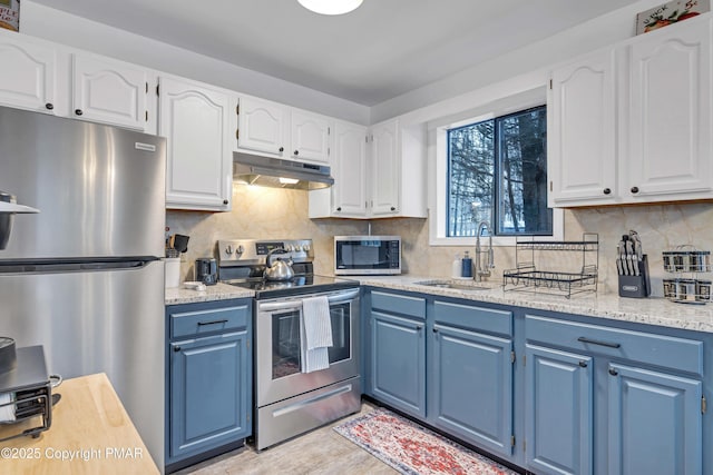 kitchen with under cabinet range hood, blue cabinetry, a sink, stainless steel appliances, and white cabinets