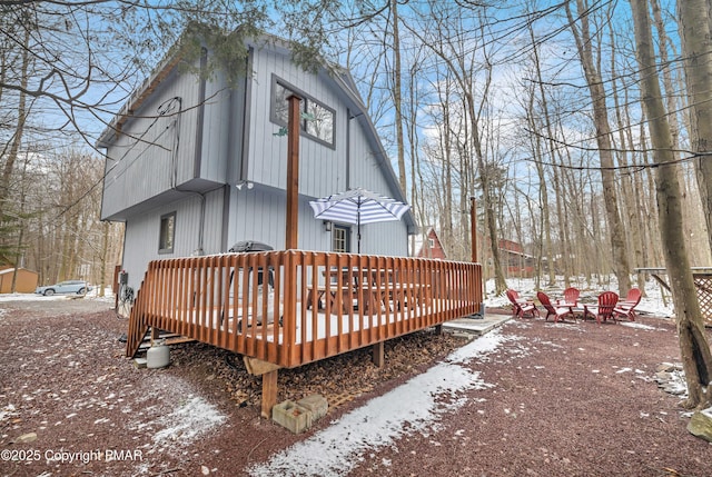 rear view of property featuring a fire pit and a deck