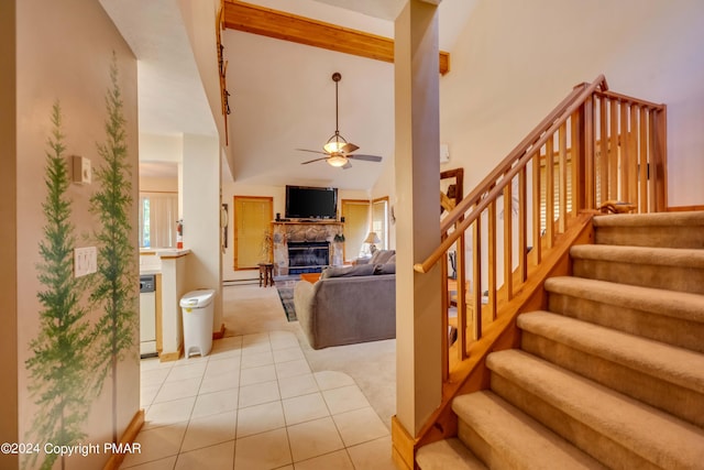 staircase with a ceiling fan, carpet floors, high vaulted ceiling, a fireplace, and tile patterned floors