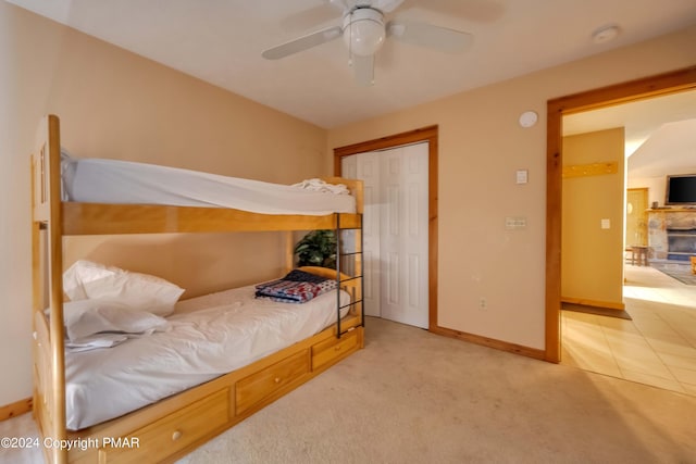 bedroom featuring a closet, baseboards, light colored carpet, and a ceiling fan