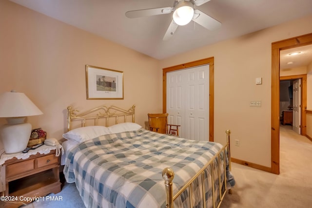 bedroom featuring a closet, light colored carpet, baseboards, and ceiling fan