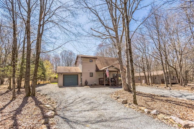 view of front of home featuring a shingled roof, covered porch, an attached garage, and gravel driveway