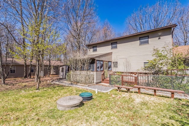 rear view of property featuring a lawn, fence, and a sunroom