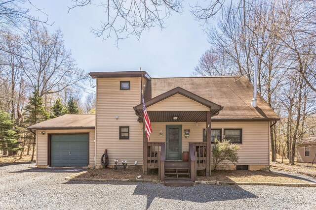 view of front facade with a porch, gravel driveway, and a garage