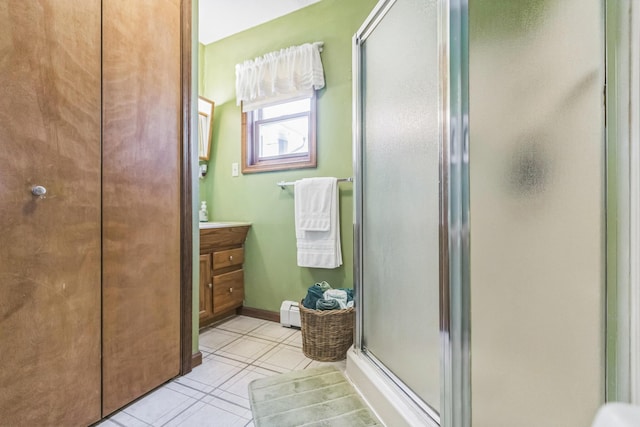 full bath featuring vanity, a baseboard heating unit, tile patterned flooring, and a shower stall