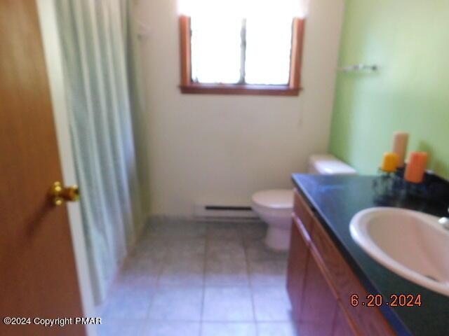 bathroom featuring a baseboard radiator, toilet, vanity, and tile patterned flooring