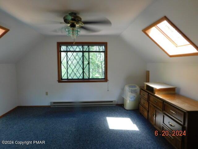 bonus room with lofted ceiling with skylight, baseboard heating, a ceiling fan, and carpet floors