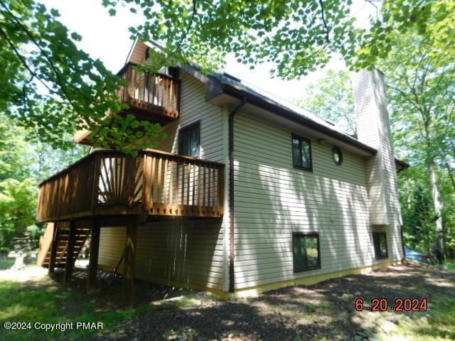 back of property featuring a deck, stairway, and a chimney