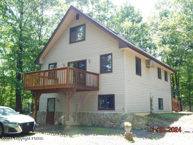 view of side of property with stone siding and a wall mounted air conditioner