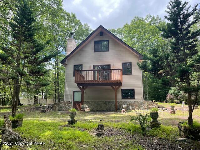 back of house featuring stone siding and a chimney