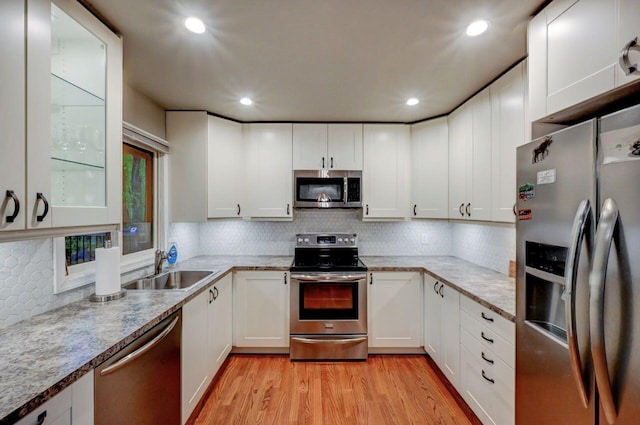 3207 Green Meadow Cir, Pocono Pines, PA 18350 - kitchen featuring appliances with stainless steel finishes, decorative backsplash, light wood-type flooring, a sink, and white cabinets