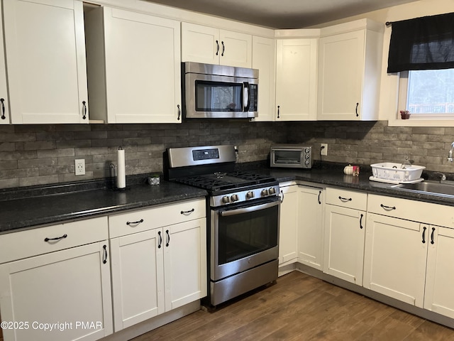 54 Vista Dr, Albrightsville, PA 18210 - kitchen with stainless steel appliances, dark countertops, backsplash, and white cabinetry