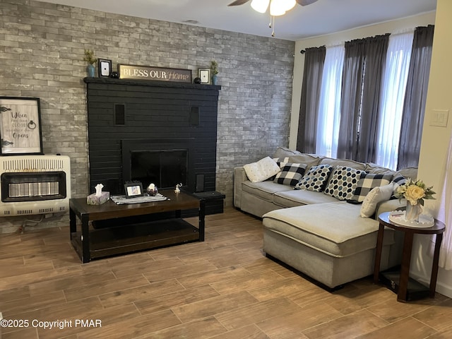 54 Vista Dr, Albrightsville, PA 18210 - living area featuring heating unit, ceiling fan, a fireplace, wood finished floors, and brick wall