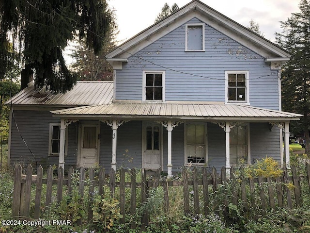 view of front facade featuring metal roof, a fenced front yard, and a porch