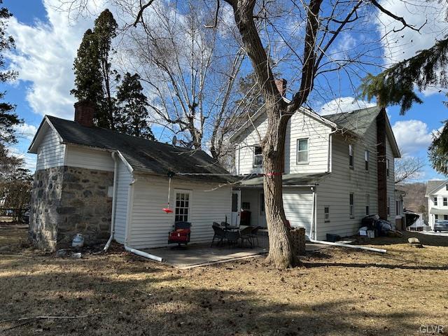 view of side of home featuring a chimney and a patio area